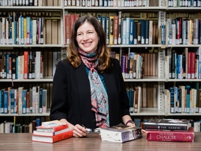 A women is standing with a few books. 