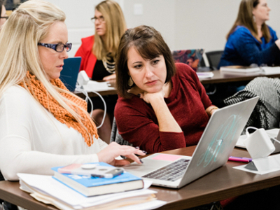 category list thumbnail - graduate students in the classroom looking at a laptop
