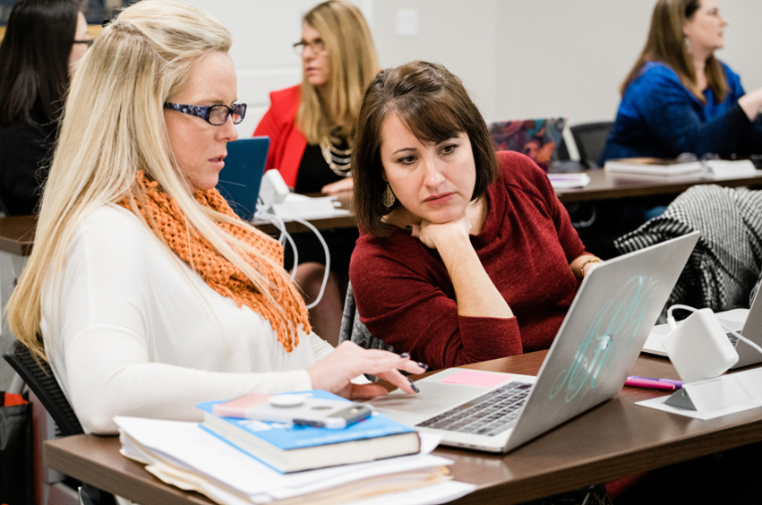 graduate students in the classroom looking at a laptop