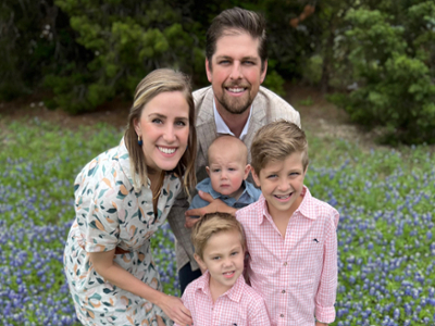 Jordan McKinney with wife and kids outside with bluebonnets in the background