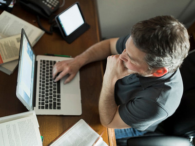 man sitting at a computer working on her personal statement for his graduate application