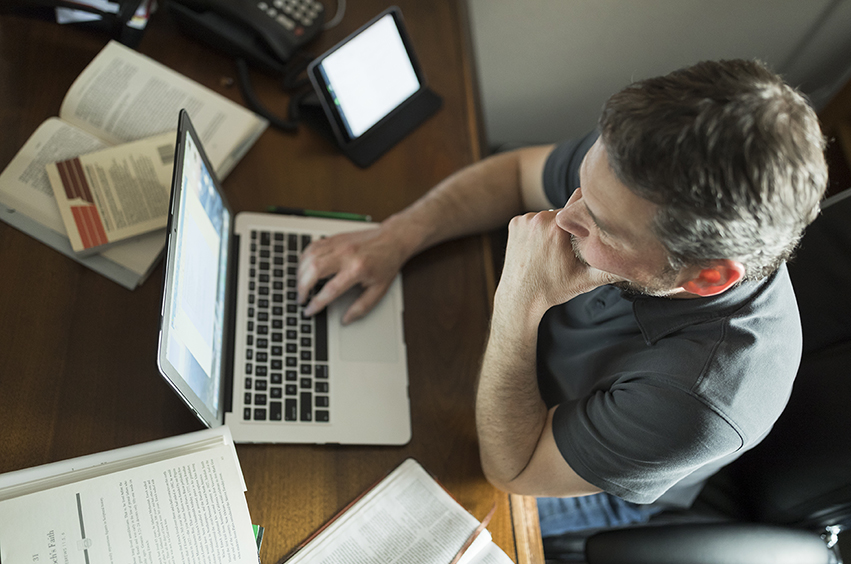 man sitting at a computer working on her personal statement for his graduate application