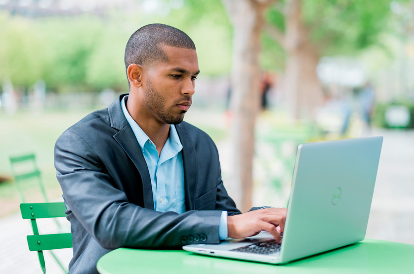 Young business student diligently studying on a laptop outdoors