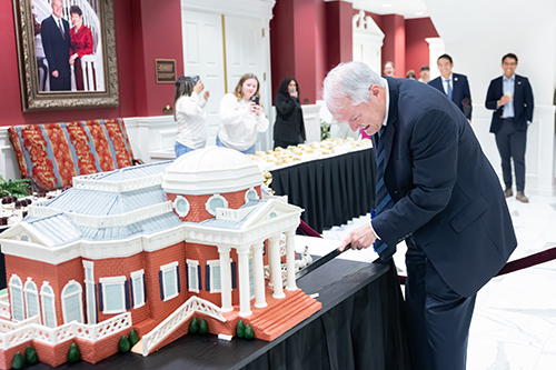 Dr. Cook cutting a replica of the National Hall cake with a sword for the Founder's Day celebration