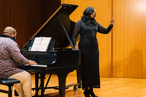 Kimberly Green standing by a black piano performing
