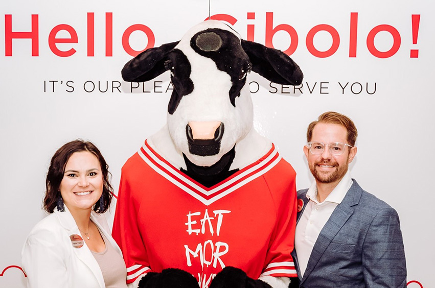 Tyler and Katee Haile standing by a Chick-fil-A cow