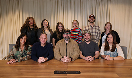Group of colleagues with Chris Clayton posing behind a conference table in an office meeting room