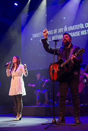 Chris Clayton standing outside with his family wearing a graduate regelia holding his master's degree