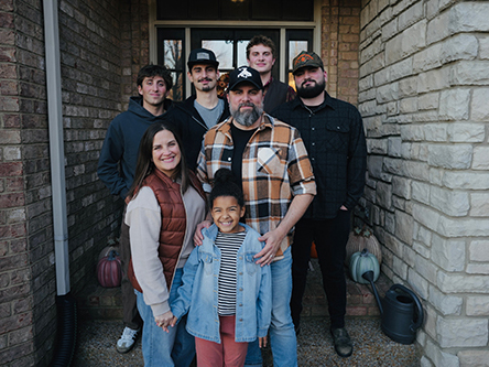 Chris Clayton standing with his family in front of the front door of a brick house