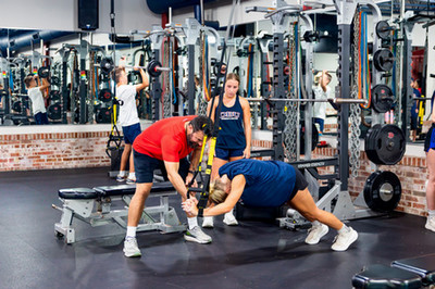 Students and trainer practicing barbell lifts at DBU