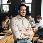 picture of a man leaning against a desk smiling