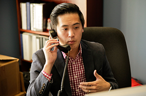 a businessman in Dallas is working on his computer while talking to someone on the phone