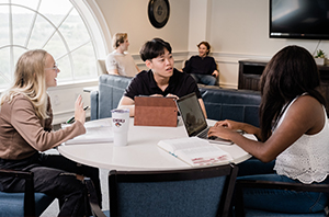 college students working on stuff sitting around a round table inside