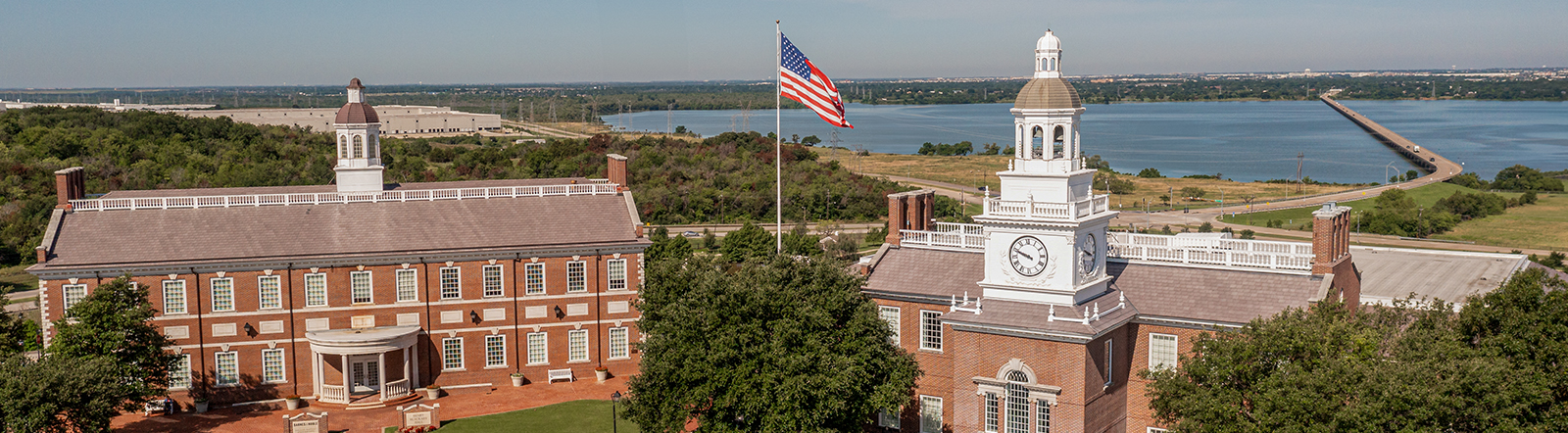 Building on the DBU campus in Dallas, Texas, with blue skies and an American flag flying
