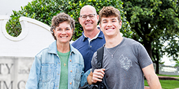 DBU student standing outside with his parents by the chapel sign