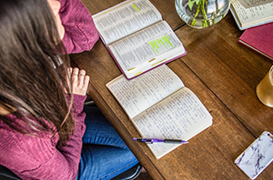 college student studying her Bible at a table