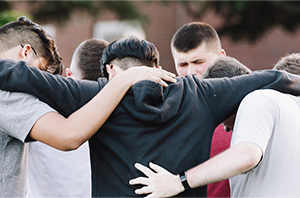 group of Christian college students praying together outside