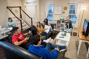 group of college students hanging out with friends in apartment living room