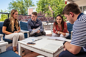 group of students studying and sitting outside around a table