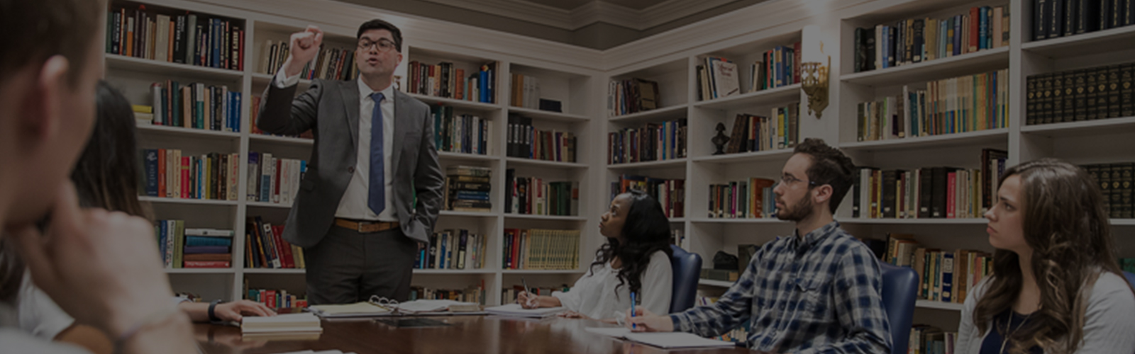 professor teaching to college students sitting around a table