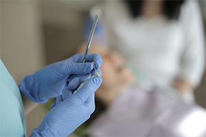 gloved hand holding dentist intsruments