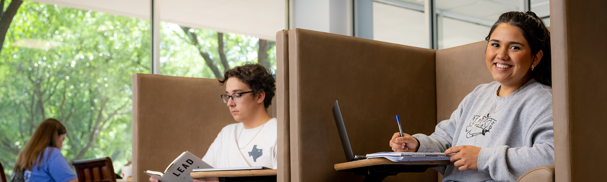 Student in the library study pods smiling at the camera
