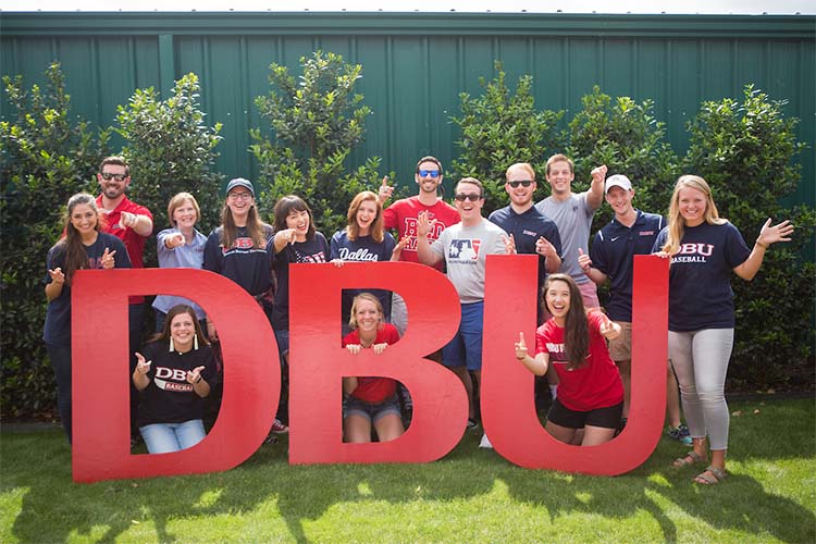 people standing outside in dallas by the red letters DBU